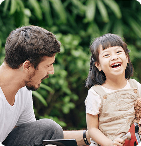 A man and girl laughing together outside.