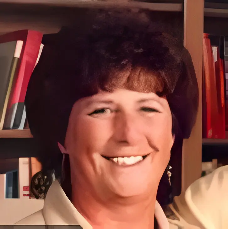 A woman with brown hair and wearing a yellow shirt.